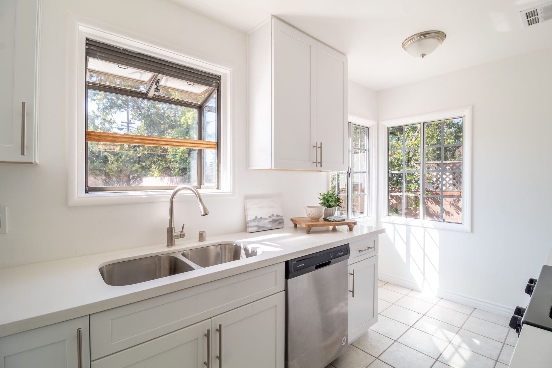 A well-lit kitchen featuring white cabinets and a modern stainless steel dishwasher in Carlsbad, CA